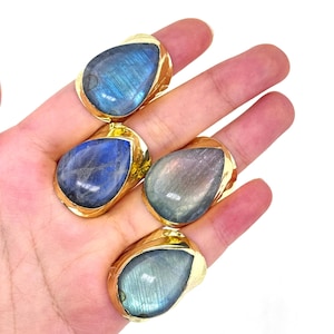 May include: Four teardrop-shaped rings with gold settings and iridescent blue labradorite stones.