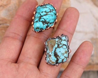 May include: Two turquoise rings with copper settings. The rings feature a unique, irregular shape and a mottled turquoise stone.
