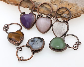 May include: Six heart-shaped charms made of copper wire and various gemstones. The charms feature amethyst, rose quartz, clear quartz, tiger's eye, moss agate, and a black and white stone.