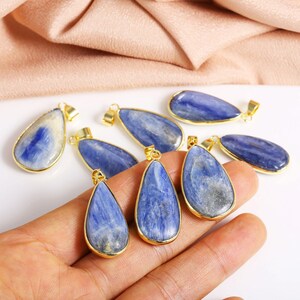 May include: A collection of eight teardrop-shaped blue kyanite pendants with gold-toned metal settings.