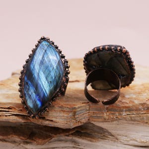 May include: Two adjustable rings with a copper setting and a large, iridescent blue labradorite gemstone.