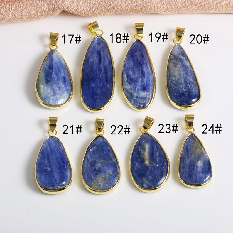 May include: Eight teardrop-shaped pendants with gold settings and blue gemstone inserts. The pendants are numbered 17 through 24.