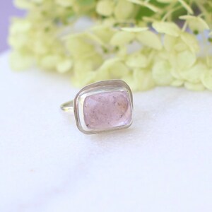 May include: A silver ring with a light pink rectangular gemstone set in a bezel setting.