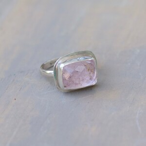 May include: A silver ring with a large, rectangular, light pink gemstone.