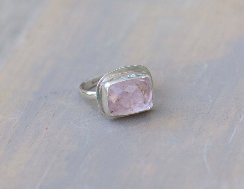 May include: A silver ring with a large, rectangular, light pink gemstone.