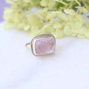 May include: A silver ring with a light pink rectangular gemstone set in a bezel setting.