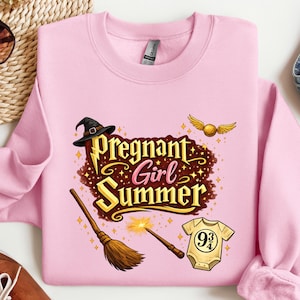 May include: A light pink sweatshirt with the words "Pregnant Girl Summer" in a gold and brown design. The design includes a witch hat, broom, wand, golden snitch, and a baby onesie.