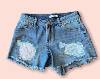 Upcycled reworked Refuge denim cutoff jeans size 4. Holes filled with quilt pieces and heart on pocket