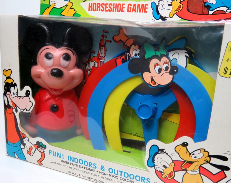 May include: A vintage Mickey Mouse horseshoe game with a red, yellow, blue and green plastic ring toss. The game features a hand-painted Mickey Mouse figure and the text "FUN! INDOORS & OUTDOORS HAND PAINTED FIGURE - NON-TOXIC COLORS WALT DISNEY PRODUCTIONS."