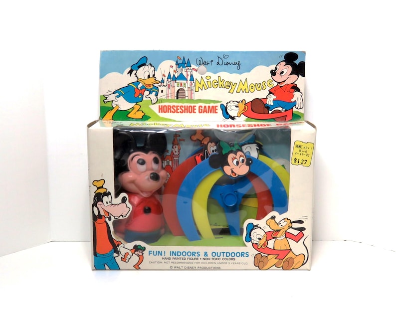 May include: A vintage Walt Disney Mickey Mouse horseshoe game in a box. The box features a colourful illustration of Mickey Mouse, Donald Duck, and Goofy. The game includes a red, yellow, blue, and green horseshoe set with a Mickey Mouse figure in the centre.