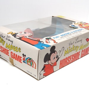 May include: A vintage Walt Disney Mickey Mouse Horseshoe Game box in blue, red and white. The box features illustrations of Mickey Mouse, Goofy and Donald Duck. The text on the box reads "Walt Disney Mickey Mouse Horseshoe Game" and "Fun Indoors & Outdoors".