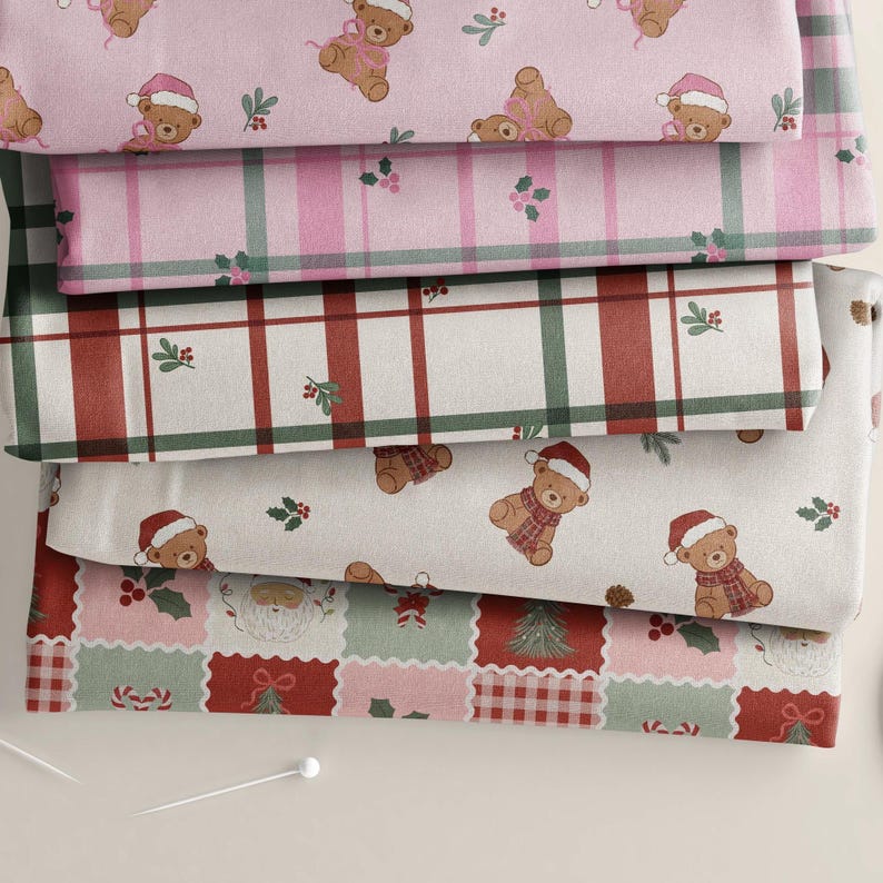 May include: Five folded pieces of fabric featuring holiday patterns. The top layer is pink with teddy bears in Santa hats. The second is a pink and green plaid. The third is a red, green, and white plaid. The fourth is white with teddy bears. The bottom layer features a grid of festive icons including Santa, candy canes, and holly.