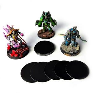May include: A set of 10 black round bases for miniature figures, along with three painted miniatures: a green space marine, a blue space marine, and a yellow and purple figure.