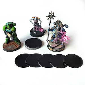 May include: A set of black round bases for miniature figures, with a stack of bases in the centre and five individual bases arranged in a row. The bases are made of a thick, durable material and are perfect for displaying miniature figures.