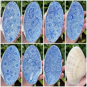 May include: A collection of seven seashells painted with intricate blue and white patterns. The shells are oval-shaped and feature various designs, including a flamingo, a starfish, and a turtle.