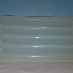 May include: A white plastic tray with five rectangular compartments. The tray is designed for holding and organizing small items.