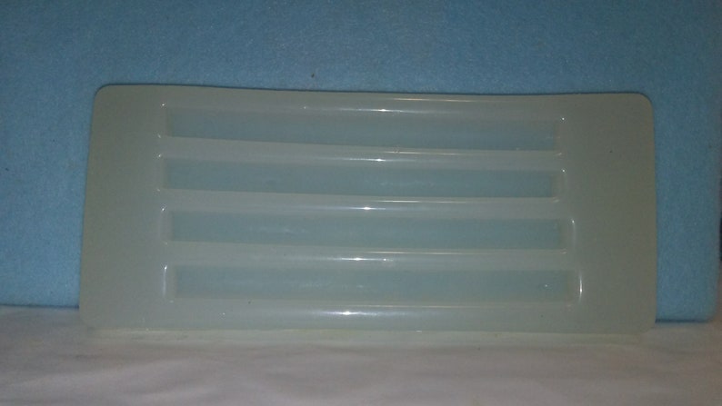May include: A white plastic tray with five rectangular compartments. The tray is designed for holding and organizing small items.
