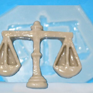 May include: A beige plastic mold of a scale of justice, a symbol of law and fairness.