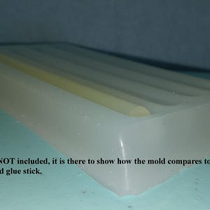 May include: A white silicone mold for making glue sticks. A glue stick is shown in the mold to demonstrate the size. "Glue stick is NOT included, it is there to show how the mold compares to a full size manufactured glue stick."