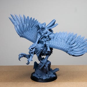 May include: A light blue figurine of a warrior riding a large bird with outstretched wings. The bird has detailed feathering, and the warrior is holding a weapon. The figurine is mounted on a black base.