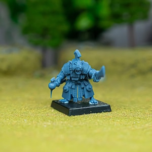 May include: A blue plastic miniature figure of a rodent-like creature standing on a black square base. The figure wears armour, has a crest on its head, and holds a curved blade in one hand and a small spherical object in the other hand.
