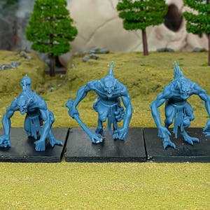 Pode incluir: Três figuras de monstros azuis sobre bases pretas. As figuras têm garras afiadas, orelhas pontudas e uma postura curvada, sugerindo um tema de jogo de fantasia ou de tabuleiro.