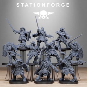 Puede incluir: Colección de figuras en miniatura grises de soldados con armadura, empuñando espadas, escudos y armas. Las figuras están sobre bases negras y dispuestas en un expositor transparente. El texto "STATIONFORGE" está en la parte superior.