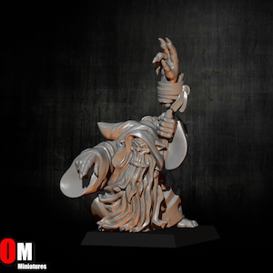 Puede incluir: Una miniatura plateada de un mago con una túnica con capucha, arrodillado con un brazo extendido y el otro sosteniendo un bastón. El mago tiene una larga barba y una cara de calavera. La base es negra y el logo "MOM Miniatures" está en la esquina inferior izquierda.