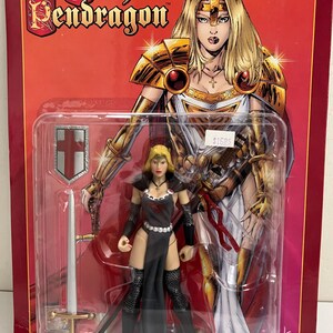 May include: A Lady Pendragon action figure in a plastic package. The figure is a woman in a black dress with a sword and shield. The packaging features a comic book style illustration of the character in gold armor.