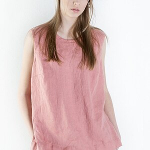 May include: A sleeveless, pink linen top with a round neckline. The top is loose-fitting and has a relaxed, casual style.