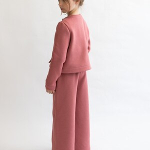 May include: A pink cropped jacket and wide-leg pants set. The jacket has a button closure and the pants have a relaxed fit.