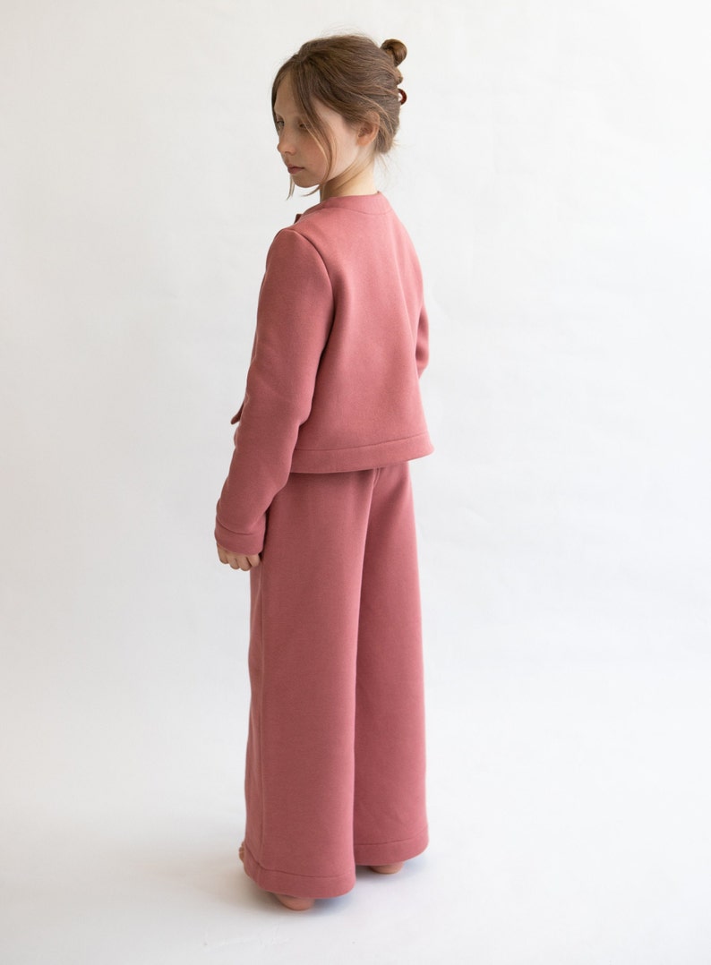May include: A pink cropped jacket and wide-leg pants set. The jacket has a button closure and the pants have a relaxed fit.