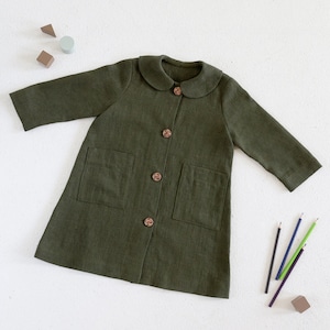 Puede incluir: Una chaqueta de lino verde con cuello de Peter Pan y botones de madera. La chaqueta tiene dos bolsillos de parche en la parte delantera.