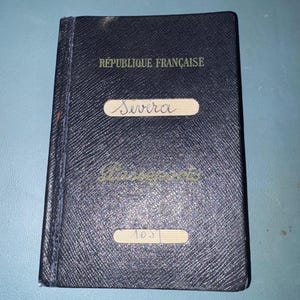 May include: A dark blue passport with the text "RÉPUBLIQUE FRANÇAISE" at the top. The name "Severa" is written on a white label. The word "Passeports" is printed in green, and the number "103" is on a white label.