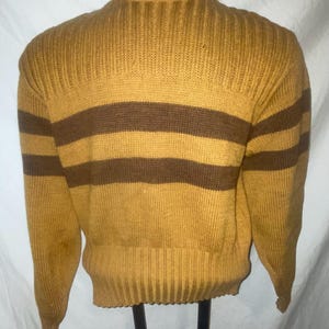 Pode incluir: Um suéter de mangas compridas com listras marrons e amarelo mostarda.