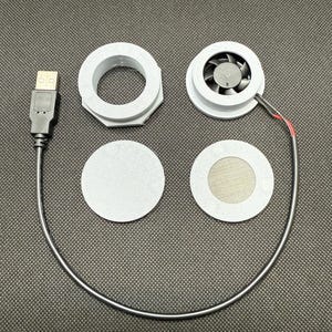 May include: A disassembled computer cooling system with a USB connector. The components include a fan, two circular pads, and two ring-shaped parts. The fan is connected to a wire with red and black insulation.