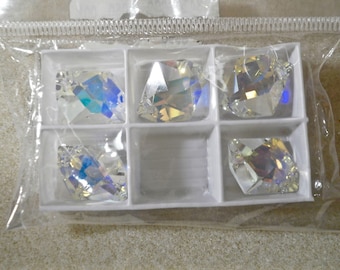 May include: Five clear, faceted, iridescent crystals are arranged in a white plastic tray with six compartments. The crystals exhibit a multi-colored shimmer and are enclosed within a clear, sealed plastic bag for protection and storage.