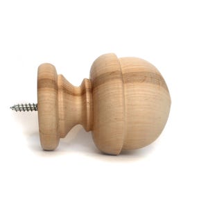 May include: A wooden finial with a rounded top and a screw for attaching it to a surface. The finial is made of light-coloured wood and has a smooth finish.