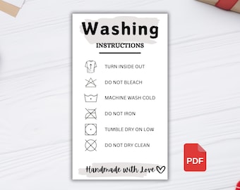 May include: A white card with black text and symbols outlining washing instructions. The text reads "Washing Instructions" and includes the following instructions: "Turn inside out", "Do not bleach", "Machine wash cold", "Do not iron", "Tumble dry on low", "Do not dry clean". The card also includes the text "Handmade with Love!" with a heart symbol.