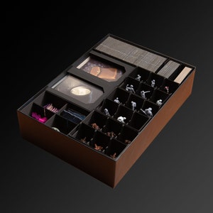 Peut inclure: Une boîte en carton marron avec un insert en mousse noire pour organiser les pièces de jeu. L'insert comporte des compartiments pour les cartes, les jetons et les figurines miniatures.