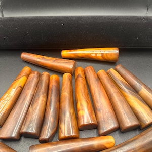 Könnte beinhalten: Eine Sammlung brauner und orangefarbener Vintage-Heizölrohre. Die Rohre haben ein konisches Design und eine glänzende Oberfläche. Einige Rohre tragen den Text "BURNHAM BOILER CO. FUEL OILS".