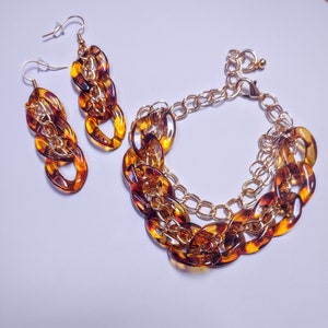 May include: A gold chain bracelet and a pair of earrings with brown and gold tortoise shell links.