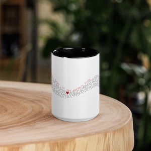 May include: White ceramic mug with a black interior, featuring a red heart and the words "...later in our perfect flow" in red. The design includes a wave of small hearts. The mug is on a wooden surface.