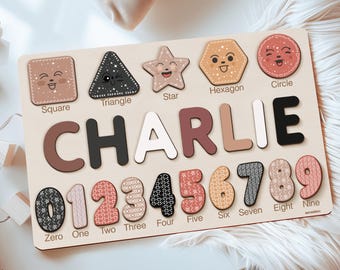 May include: A wooden educational puzzle board featuring the name CHARLIE in large letters, with cutouts for shapes labeled Square, Triangle, Star, Hexagon, Circle, and numbers zero through nine, each decorated with various patterns and colors.