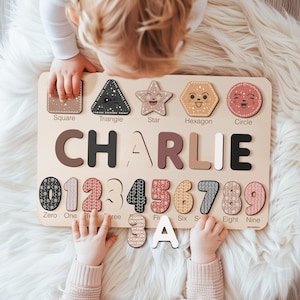 May include: Wooden educational puzzle board with the name "CHARLIE" and numbers 0-9. The board includes shapes like a square, triangle, star, hexagon, and circle. The puzzle pieces are in various colors and patterns.