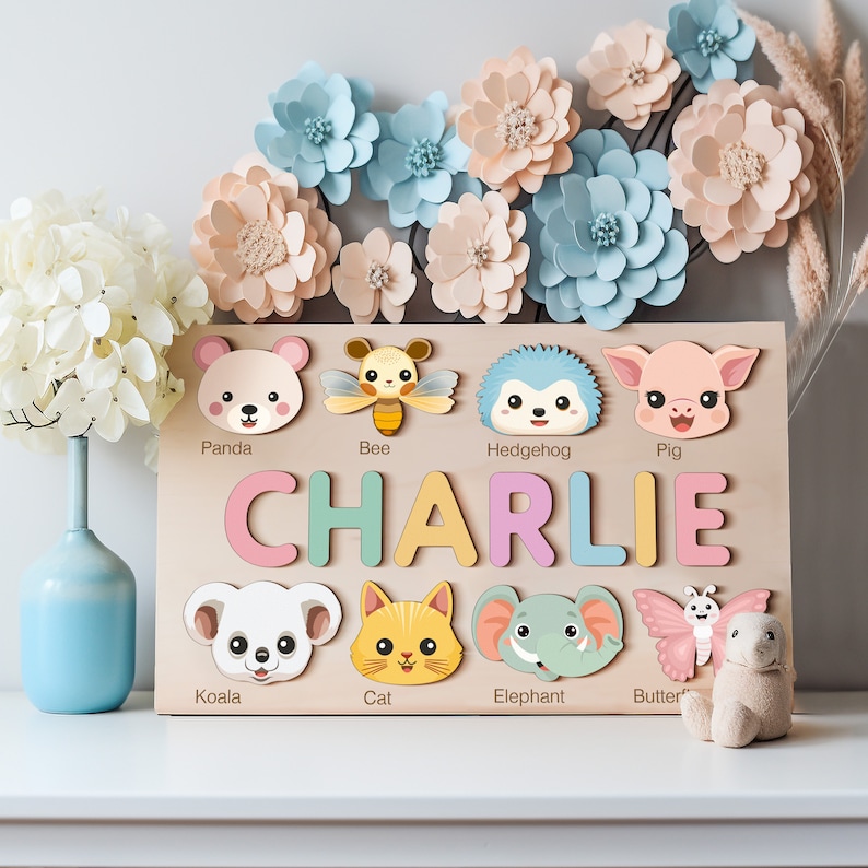 Peut inclure: Un puzzle de nom personnalis&eacute; en bois avec des personnages d'animaux color&eacute;s. Le puzzle pr&eacute;sente le nom "CHARLIE" en lettres color&eacute;es et comprend des animaux comme un panda, une abeille, un h&eacute;risson, un cochon, un koala, un chat, un &eacute;l&eacute;phant et un papillon.