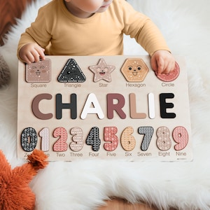Peut inclure: Un jouet éducatif en bois avec des formes, des chiffres et des lettres colorés. Les formes comprennent un carré, un triangle, une étoile, un hexagone et un cercle. Les lettres épellent le nom "CHARLIE". Les chiffres sont de 0 à 9.