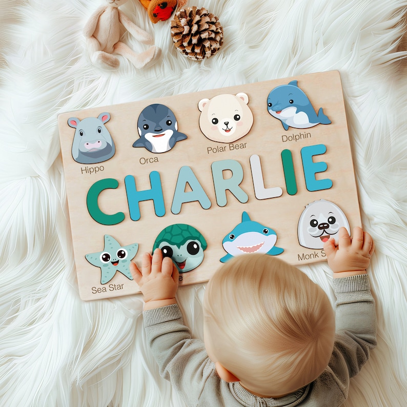 Peut inclure: Un puzzle en bois avec des illustrations d'animaux color&eacute;s et le nom "CHARLIE" &eacute;crit en grandes lettres color&eacute;es. Le puzzle est con&ccedil;u pour les enfants et pr&eacute;sente une vari&eacute;t&eacute; de cr&eacute;atures marines, notamment un hippopotame, une orque, un ours polaire, un dauphin, une &eacute;toile de mer, une tortue, un requin et un phoque moine.