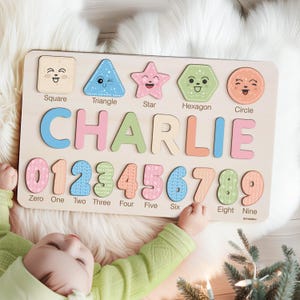 May include: A wooden puzzle board with colourful shapes, numbers, and letters. The shapes include a square, triangle, star, hexagon, and circle. The numbers are 0 through 9. The letters spell out the name "CHARLIE".