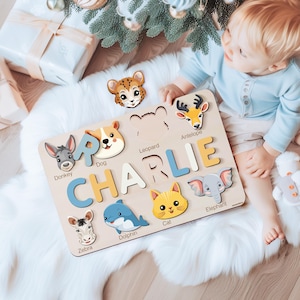 May include: A wooden puzzle featuring the name "CHARLIE" with colorful letters and animal illustrations. The puzzle includes a donkey, dog, leopard, antelope, cat, elephant, zebra, and dolphin.